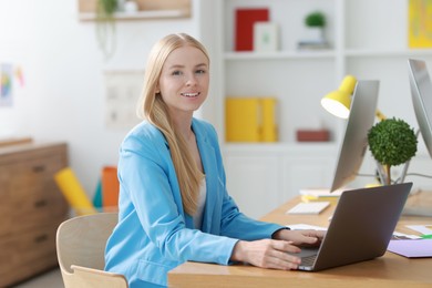 Photo of Designer working with laptop at table in office