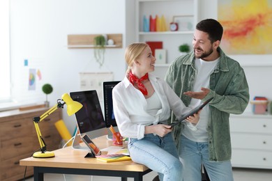 Professional designers working with tablet together in office