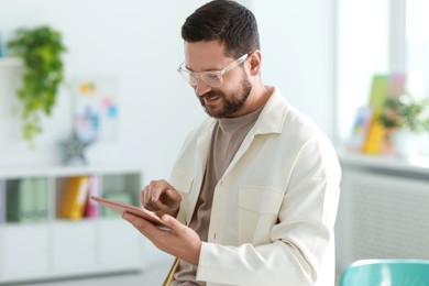 Smiling designer with tablet working in office