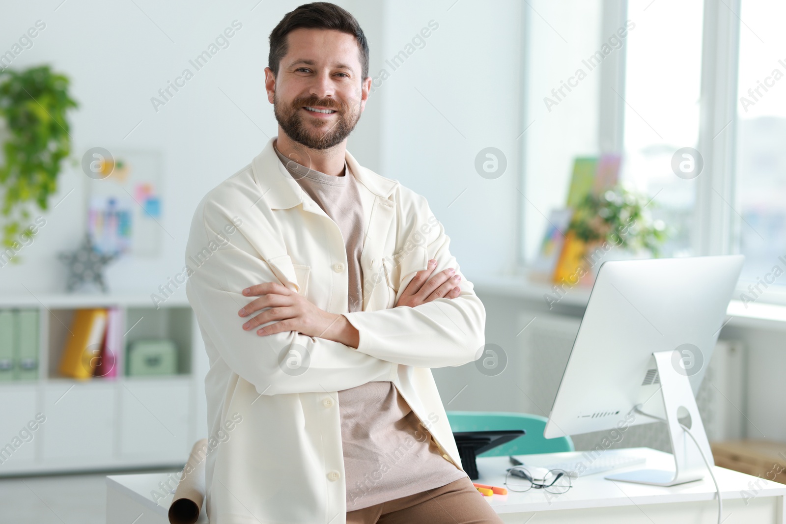 Photo of Portrait of smiling designer near table in office