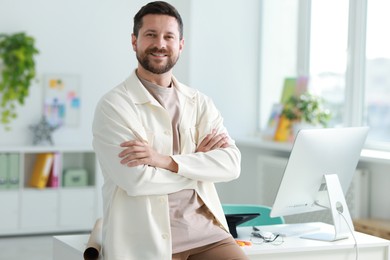 Photo of Portrait of smiling designer near table in office