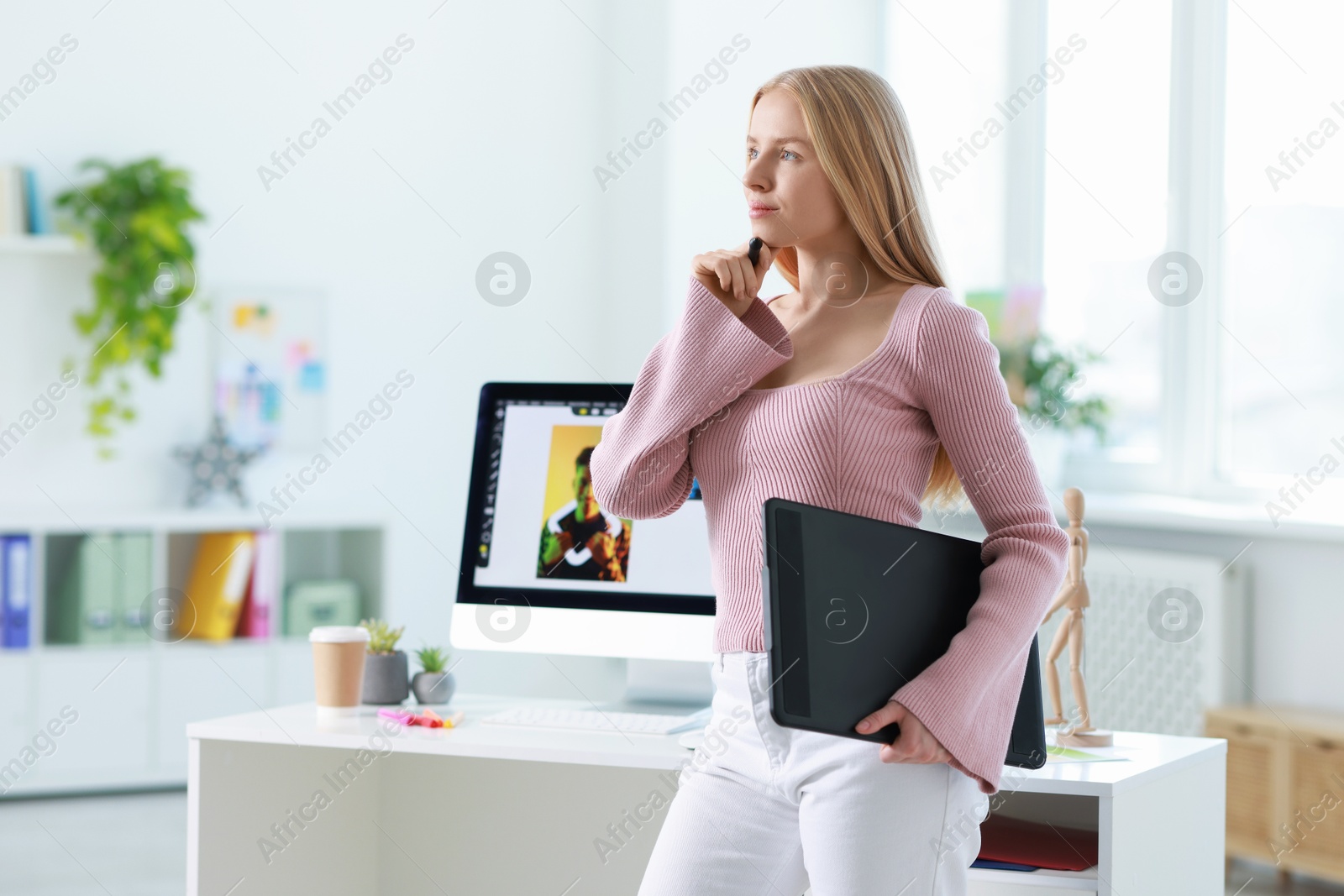 Photo of Beautiful young designer with tablet in office