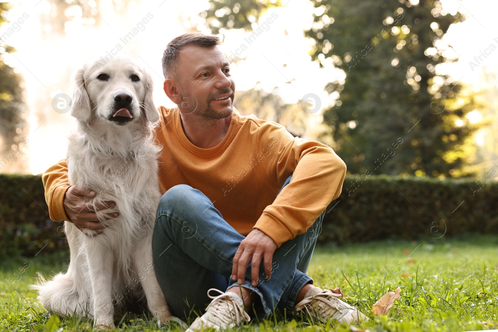 Photo of Smiling man with cute Golden Retriever dog on spring day