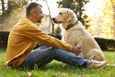 Photo of Smiling man with cute Golden Retriever dog on spring day