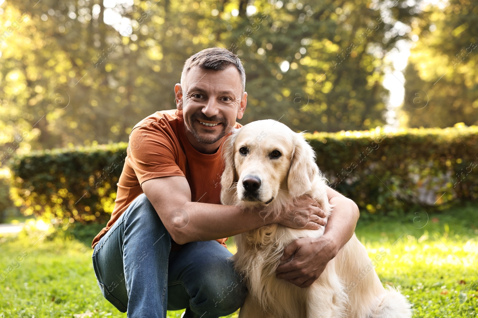 Photo of Smiling man with cute Golden Retriever dog on spring day