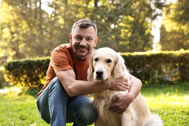 Smiling man with cute Golden Retriever dog on spring day