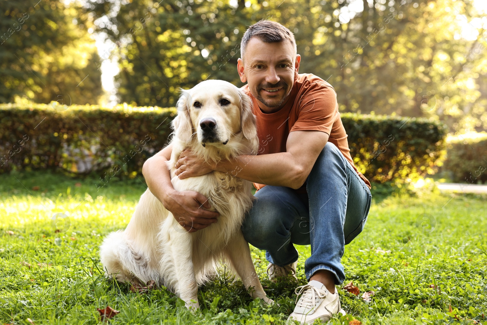 Photo of Smiling man with cute Golden Retriever dog on spring day