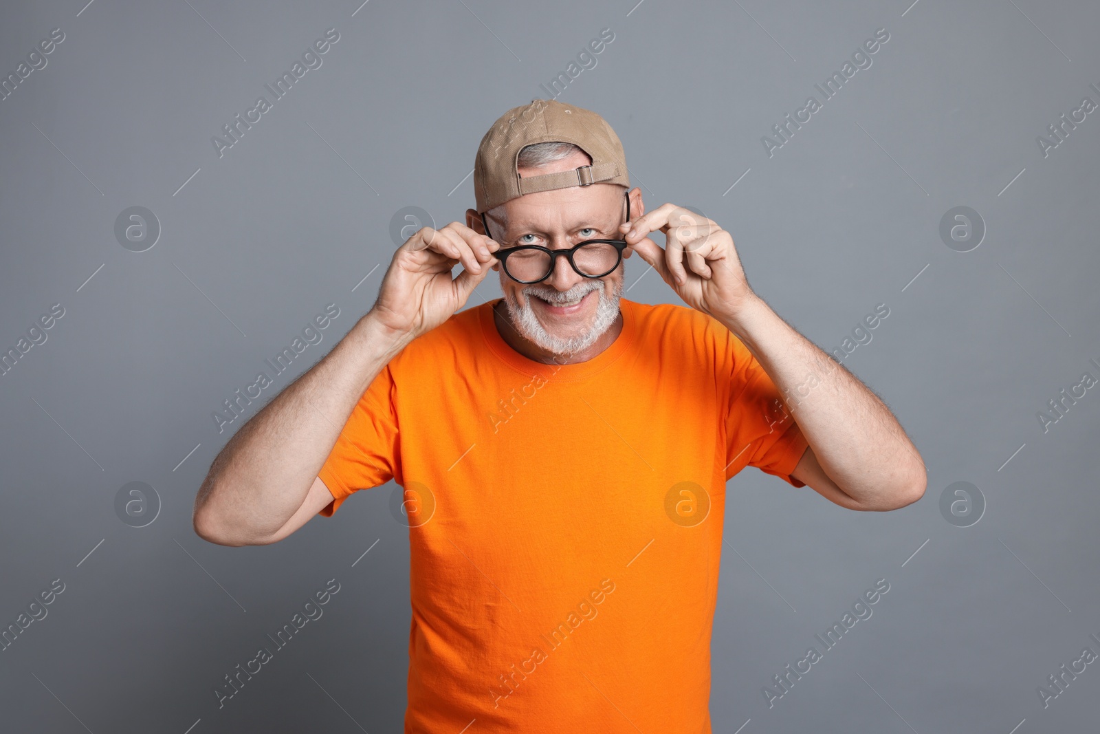 Photo of Portrait of funny senior man in glasses on grey background