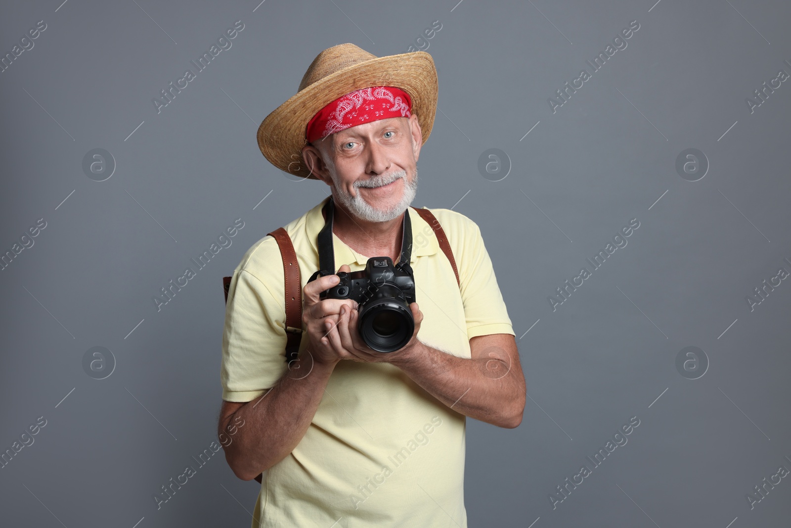 Photo of Portrait of handsome senior man with camera on grey background