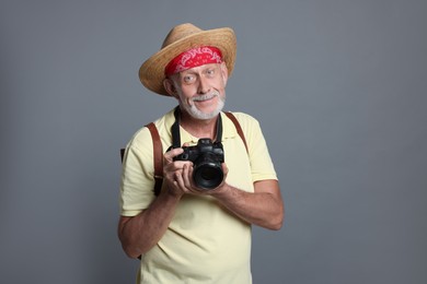 Portrait of handsome senior man with camera on grey background