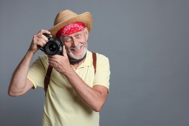 Portrait of happy senior man with camera on grey background. Space for text