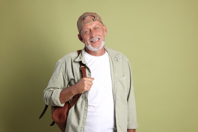 Portrait of happy senior man with backpack on green background