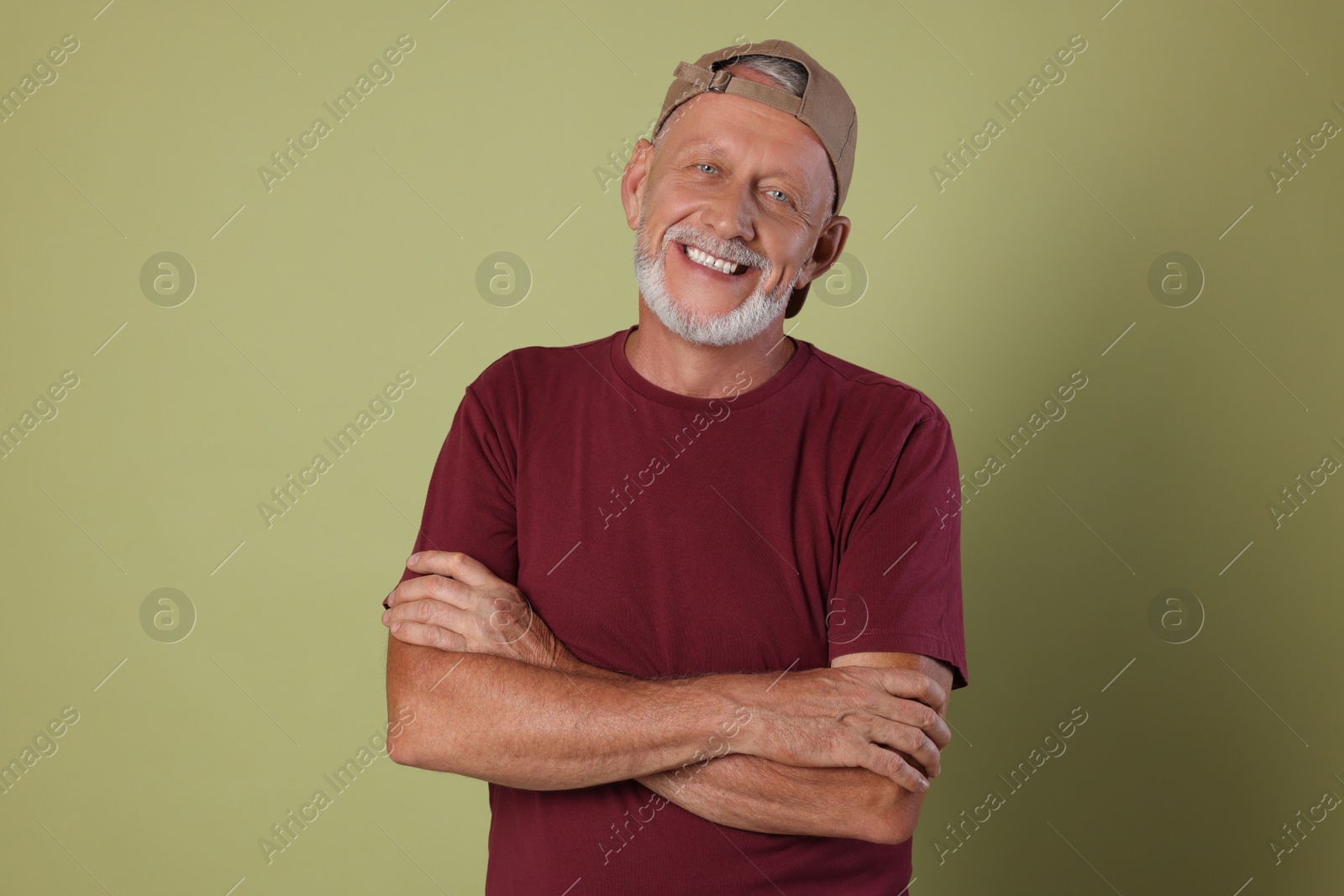 Photo of Portrait of happy senior man with crossed arms on green background