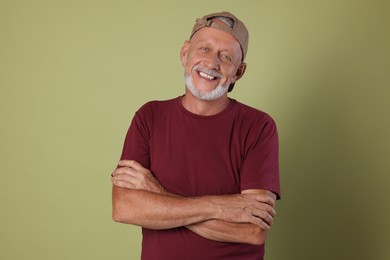 Portrait of happy senior man with crossed arms on green background