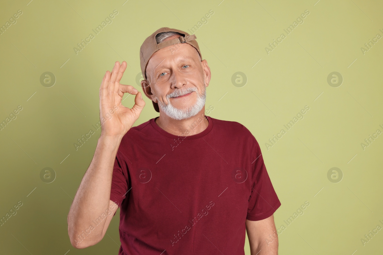 Photo of Portrait of handsome senior man showing ok gesture on green background