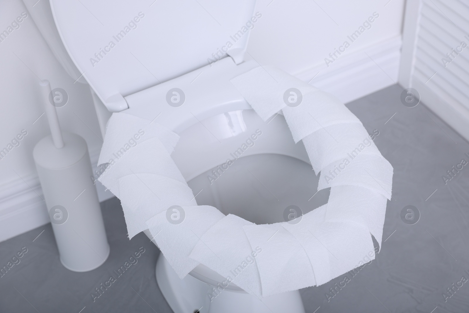 Photo of Toilet seat with paper tissues in bathroom