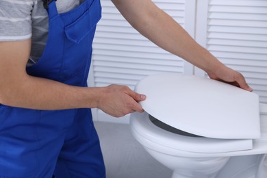 Man fixing toilet seat in bathroom, closeup