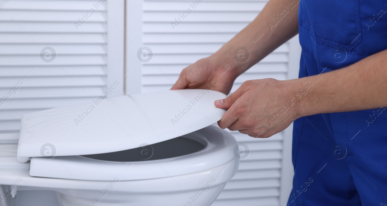 Photo of Man fixing toilet seat in bathroom, closeup