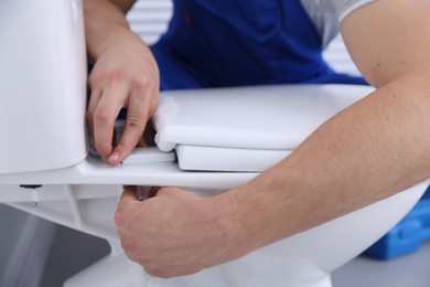 Photo of Man fixing toilet seat in bathroom, closeup