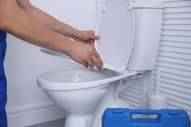 Photo of Man fixing toilet seat in bathroom, closeup