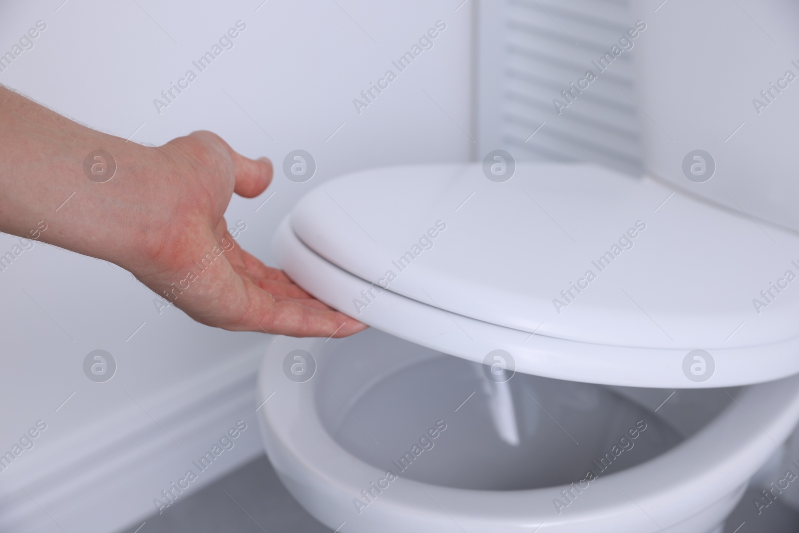 Photo of Man closing toilet seat in bathroom, closeup