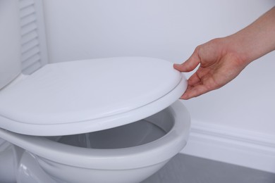 Photo of Man closing toilet seat in bathroom, closeup