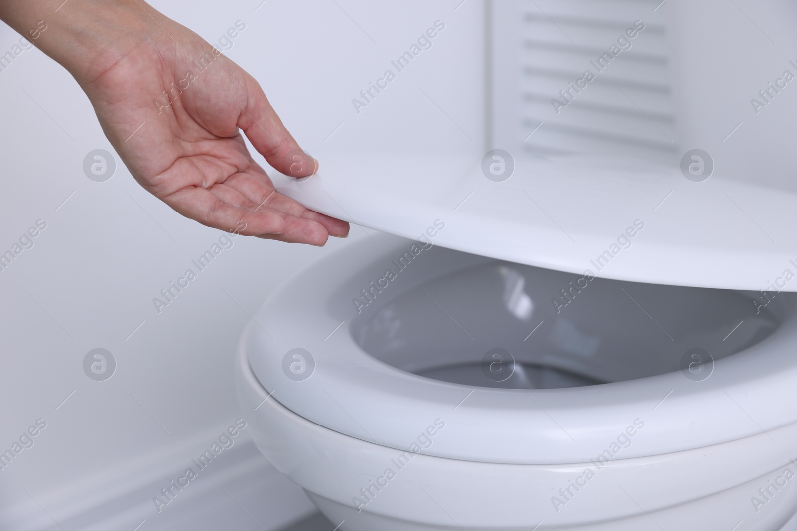 Photo of Woman closing toilet seat in bathroom, closeup