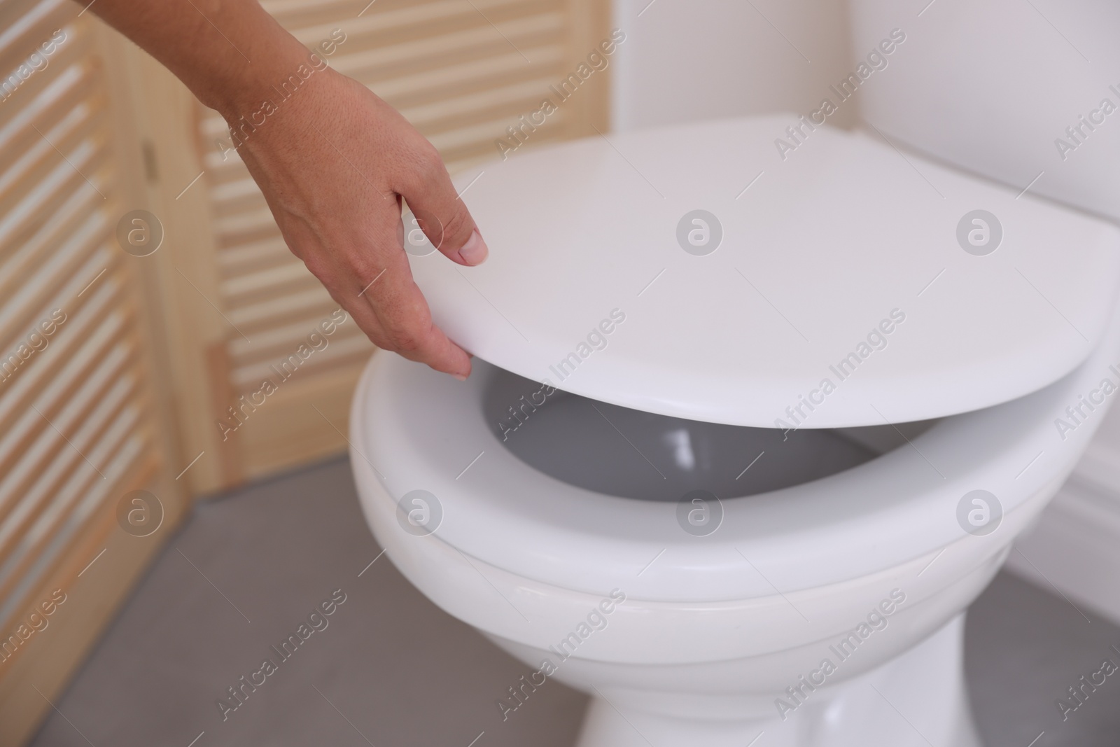 Photo of Woman closing toilet seat in bathroom, closeup