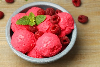 Photo of Delicious raspberry sorbet, fresh berries and mint in bowl on wooden table, closeup