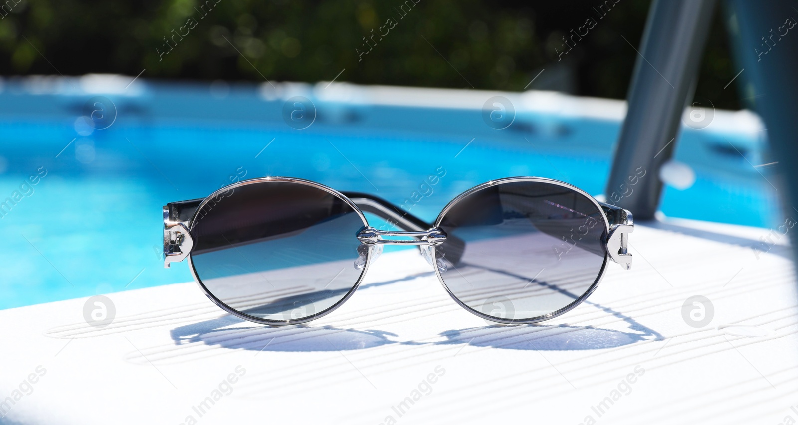 Photo of One pair of sunglasses near swimming pool outdoors