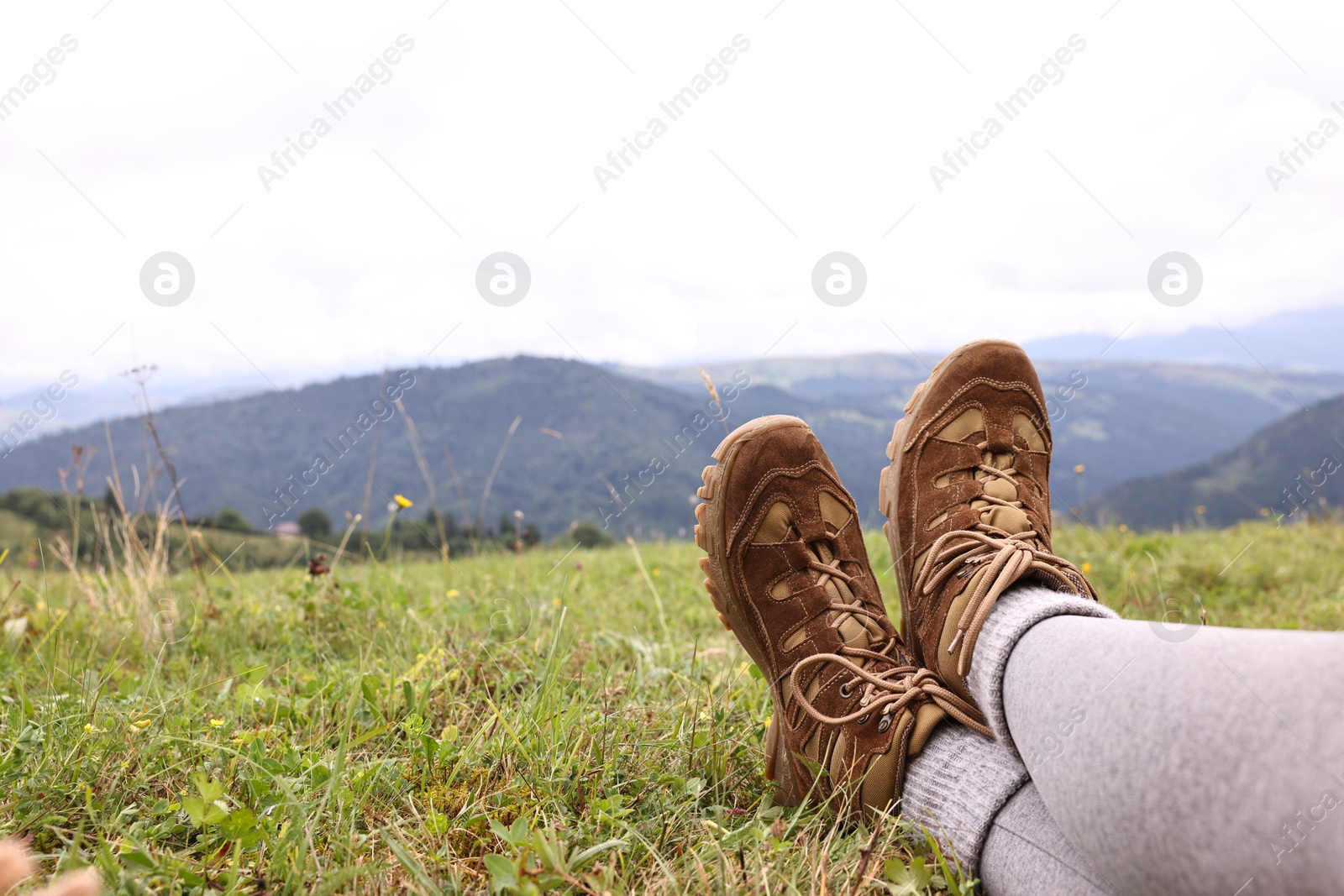 Photo of Young hiker wearing trekking shoes in mountains, closeup. Space for text