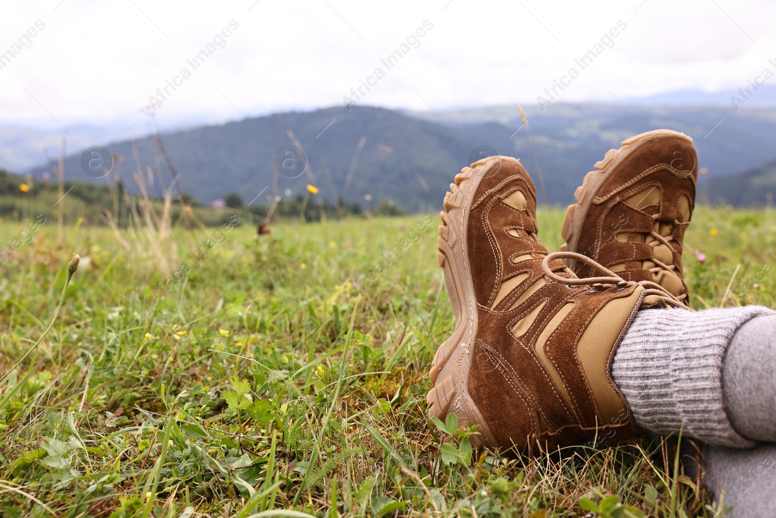 Photo of Young hiker wearing trekking shoes in mountains, closeup. Space for text