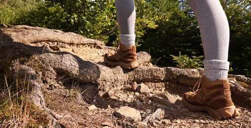 Photo of Young hiker in trekking shoes walking outdoors, closeup