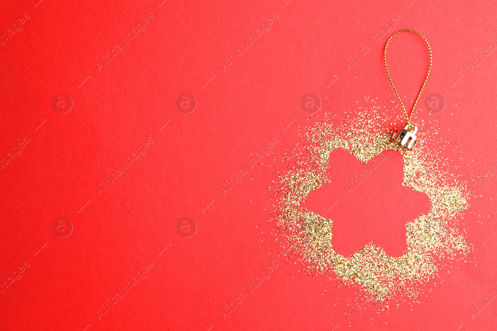 Photo of Christmas ornament made of golden glitter on red background, top view. Space for text