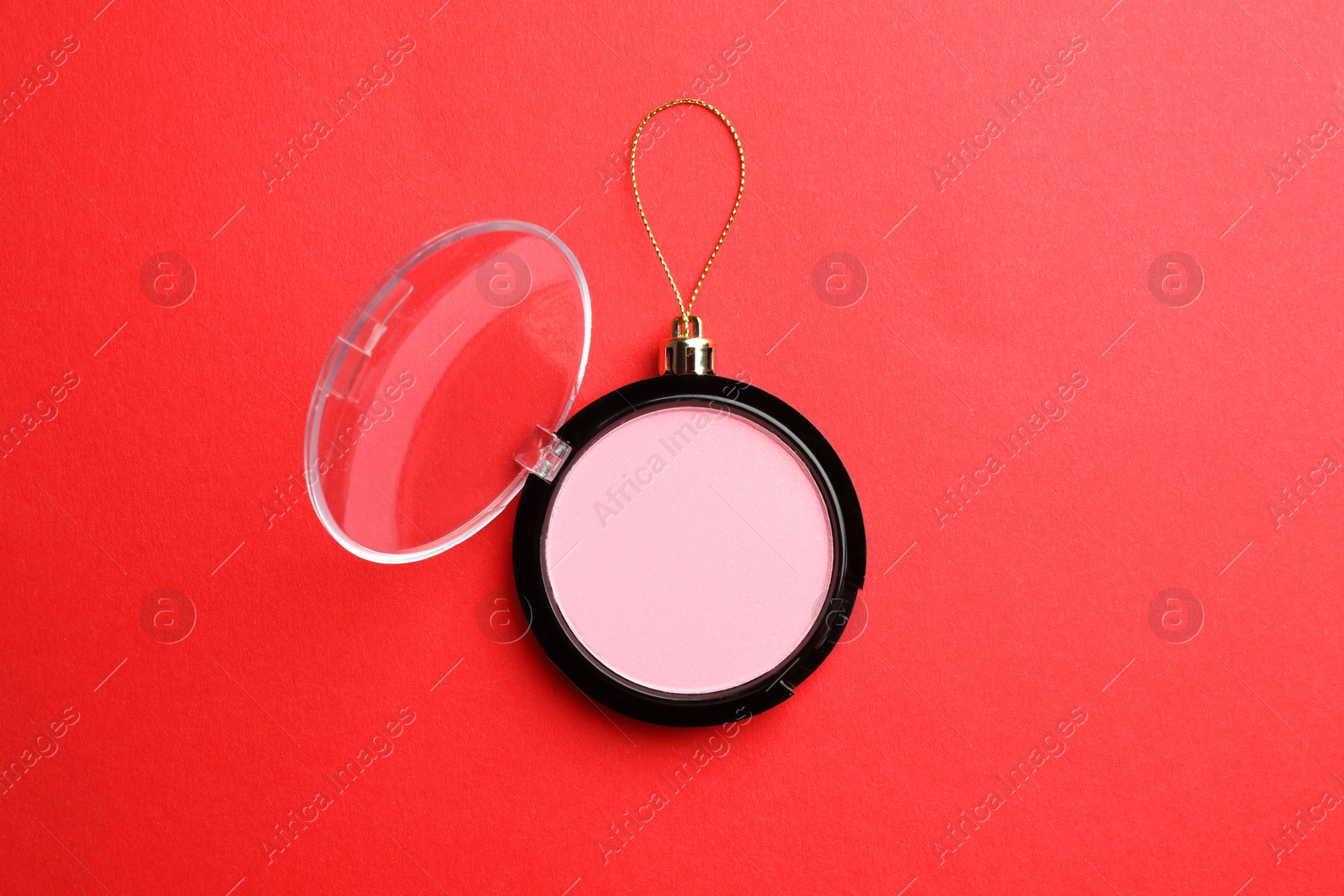 Photo of Blusher in shape of Christmas ball on red background, top view