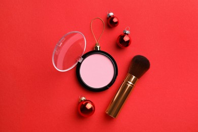 Photo of Blusher in shape of Christmas ball and brush on red background, flat lay