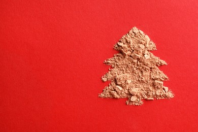 Photo of Christmas tree made of face powder on red background, top view. Space for text