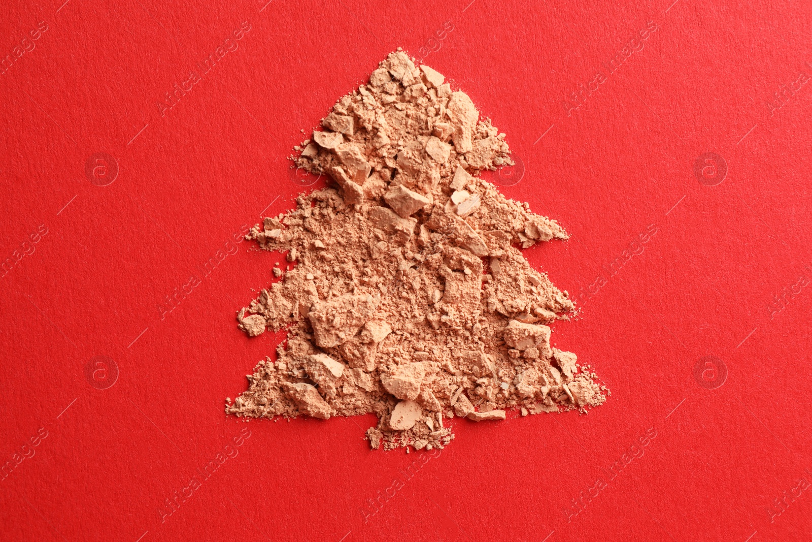 Photo of Christmas tree made of face powder on red background, top view