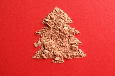 Photo of Christmas tree made of face powder on red background, top view