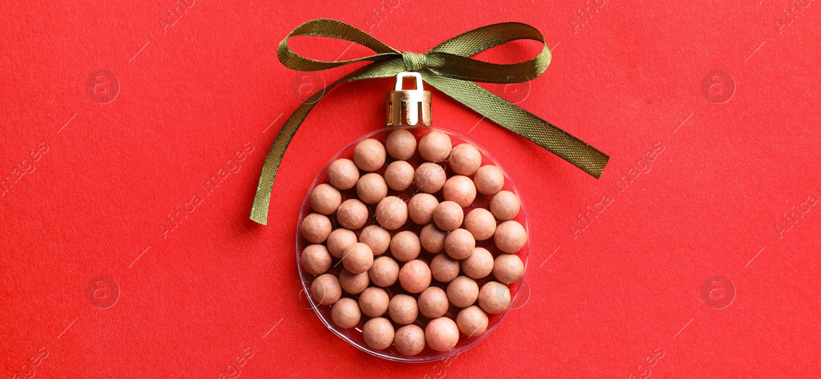 Photo of Christmas ball made with blush on red background, top view