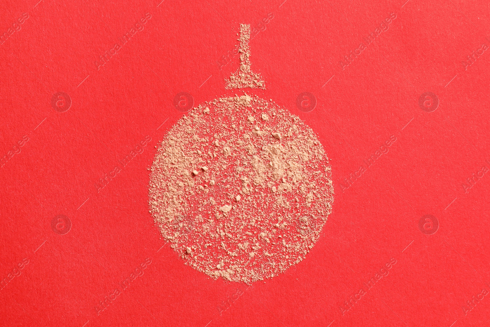 Photo of Christmas ball made with face powder on red background, top view