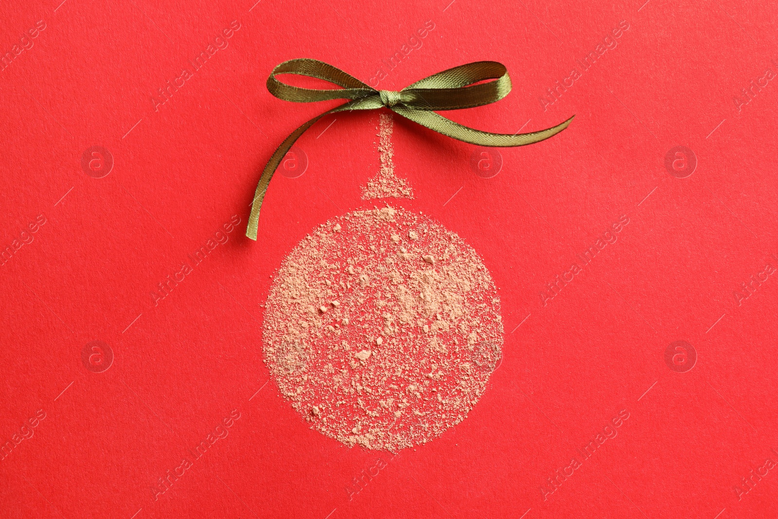 Photo of Christmas ball made with face powder on red background, top view