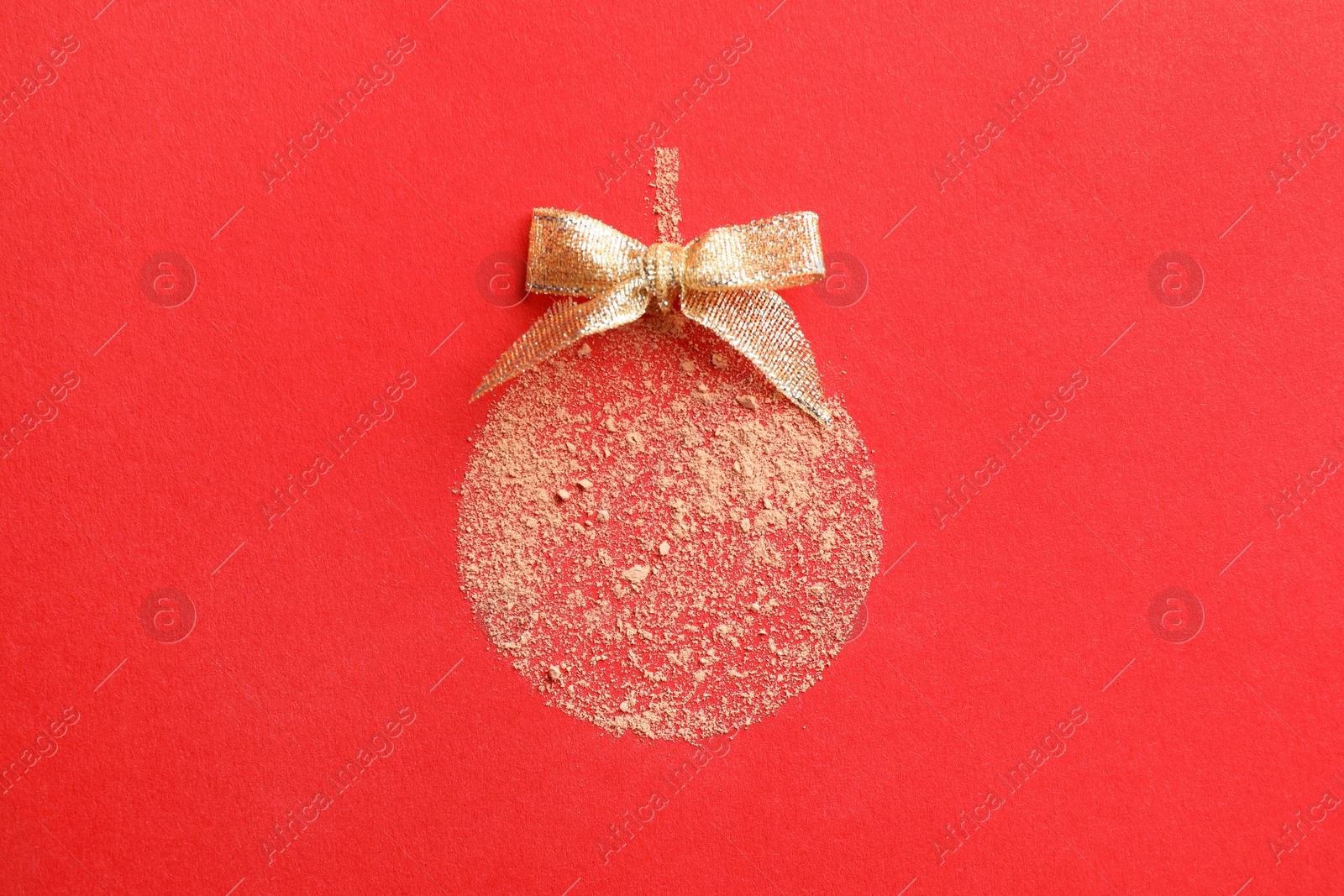 Photo of Christmas ball made with face powder on red background, top view