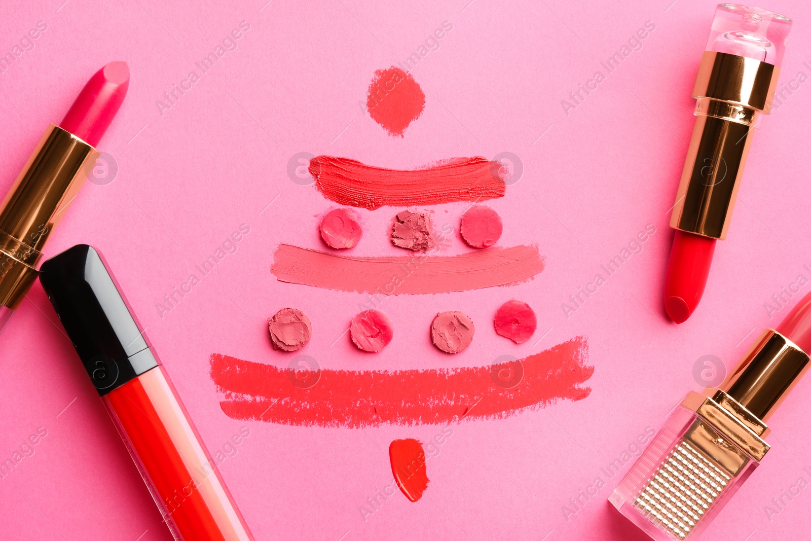 Photo of Christmas tree drawn with lipsticks on pink background, flat lay