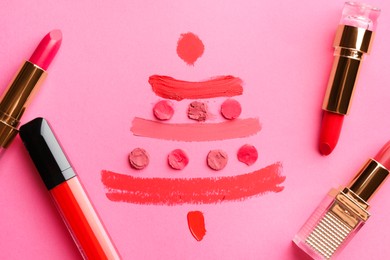 Photo of Christmas tree drawn with lipsticks on pink background, flat lay