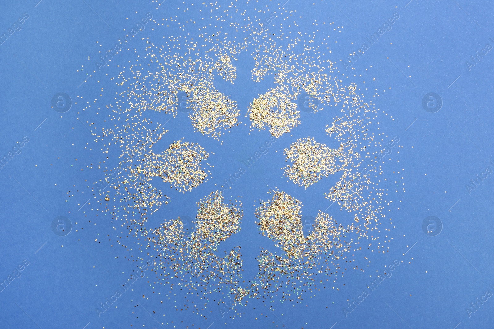 Photo of Snowflake made of golden glitter on blue background, top view