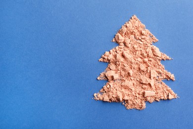 Photo of Christmas tree made with face powder on blue background, top view. Space for text