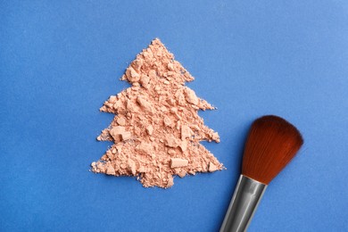 Photo of Christmas tree made with face powder and brush on blue background, top view