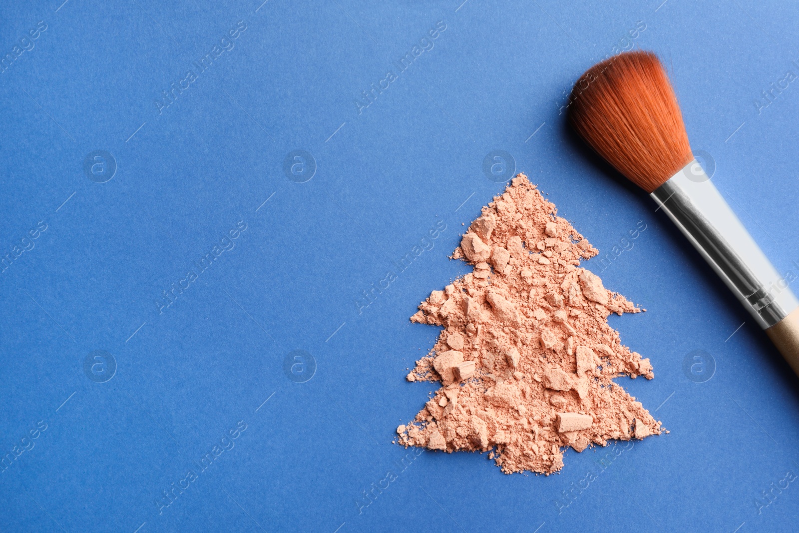 Photo of Christmas tree made with face powder and brush on blue background, top view. Space for text