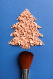 Photo of Christmas tree made with face powder and brush on blue background, top view